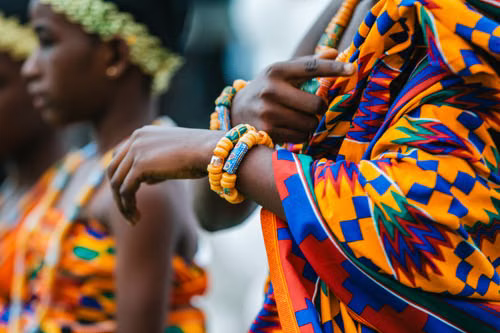 Close-up of beaded bracelets and kente cloth