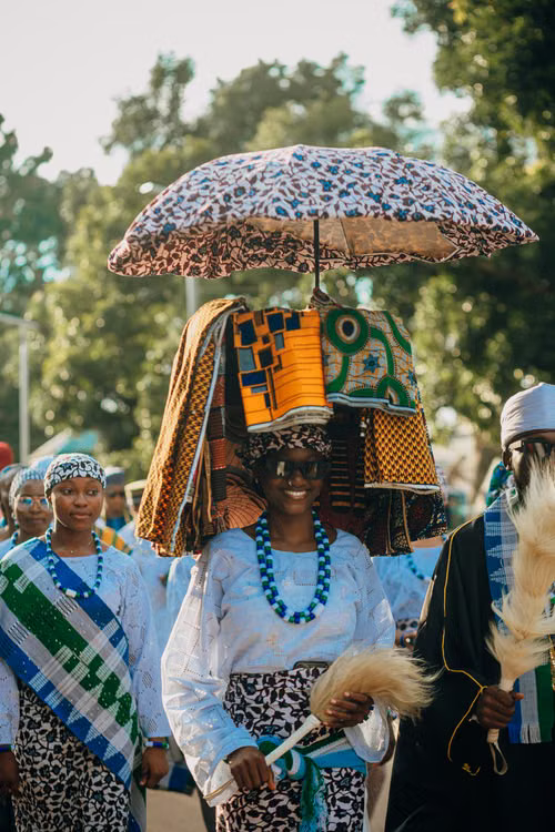 A woman in an elaborate ceremonial headdress and umbrella
