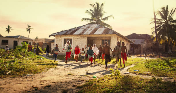Children running through a village at sunset